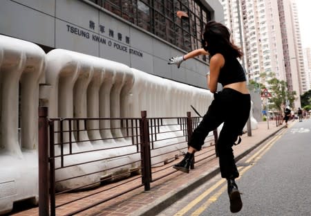 An anti-extradition bill protester throws a stone at a police station in Tseung Kwan O residential district, in Hong Kong