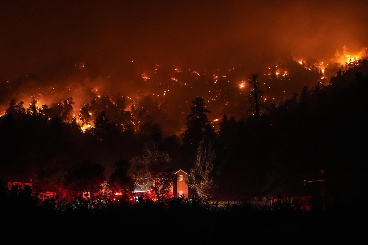 Firetrucks are seen around a building as scorched trees smolder during the Bridge Fire in Wrightwood, Calif., Wednesday.