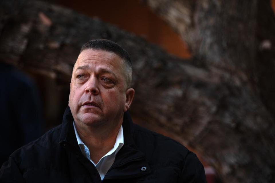 Eric Acosta, 53, is sitting in a peaceful outdoor courtyard at Amistad de