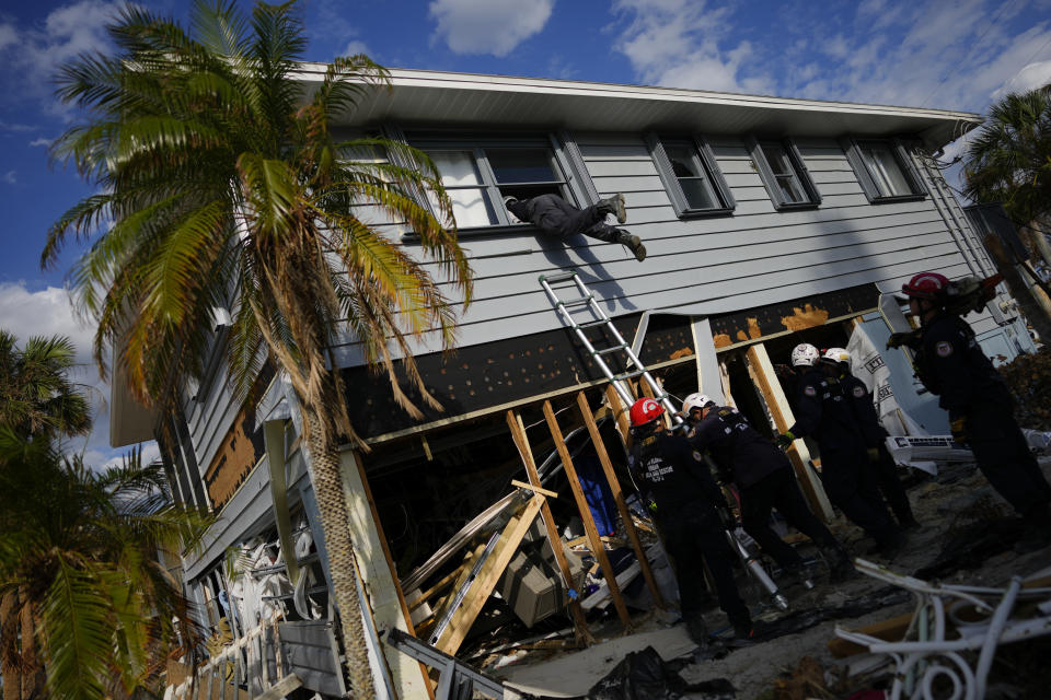 Miembros de una fuerza de búsqueda y rescate urbano de Florida ingresan a una casa a través de una ventana rota para confirmar que no hay personas o restos humanos en la vivienda, una semana después del paso del huracán Ian, en Fort Myers Beach, Florida, el 5 de octubre de 2022. (AP Foto/Rebecca Blackwell)