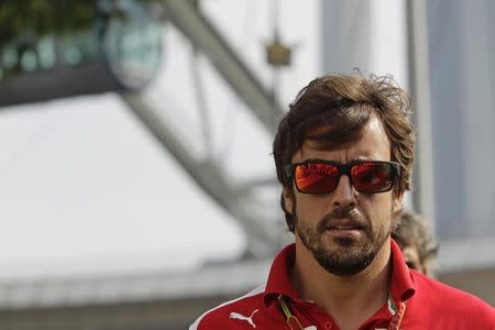 Ferrari Formula One driver Fernando Alonso of Spain arrives at the paddock before the first practice session of Singapore F1 Grand Prix September 19, 2014. REUTERS/Tim Chong