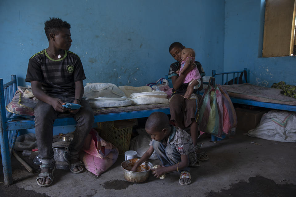 Daniel Gebremariam, un refugiado de Tigray de 11 años, sostiene a su hermana Turfu, de 4 meses en brazos, mientras su hermano Micheale, de 5, junto a su tío Goytom Tsegay (izquierda), de 19 años, en albergue donde vive la familia en Hamdayet, en el este de Sudán, cerca de la frontera con Etiopía, el 21 de marzo de 2021. (AP Foto/Nariman El-Mofty)