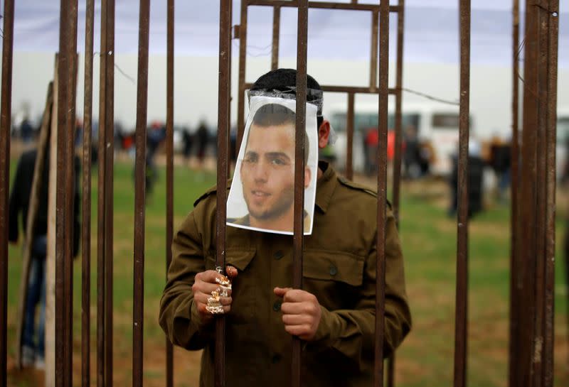 FILE PHOTO: Palestinian man playing the role of Israeli soldier Oron Shaul stands in a mock jail during a rally in solidarity with Palestinian prisoners held in Israeli jails, in the northern Gaza Strip