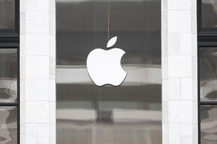 A cutout of the Apple logo hangs in a store window.