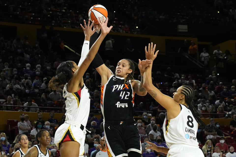 Phoenix Mercury center Brittney Griner (42) drives between Las Vegas Aces forward A'ja Wilson and center Liz Cambage (8) during the first half of a WNBA basketball game Sunday, Oct. 3, 2021, in Phoenix. (AP Photo/Rick Scuteri)