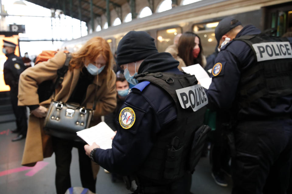 French police officers check passengers of a train from Amsterdam and Brussels at Gare du Nord station in Paris, Monday, Feb. 1, 2021. France says it's closing its borders to people arriving from outside the European Union starting Sunday to try to stop the growing spread of new variants of the virus and avoid a third lockdown. (AP Photo/Francois Mori)