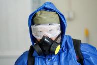 A health worker wearing a protective suit sprays disinfectant outside of a building during an awareness campaign for coronavirus disease (COVID-19), in Jalalabad