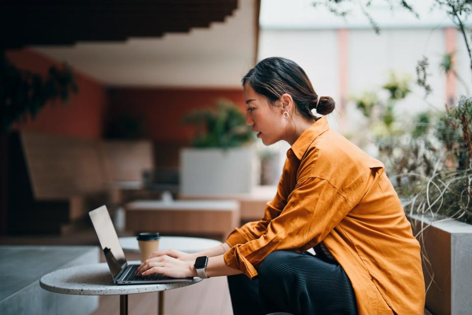 image of woman typing on computer at a cafe