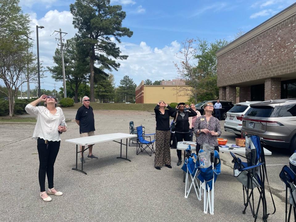 Employees at the Crye-Leike Realty office on Forest Hill Irene Road in Germantown watch the total solar eclipse from the office parking lot on Monday, April 8, 2024 in Mephis, Tenn.