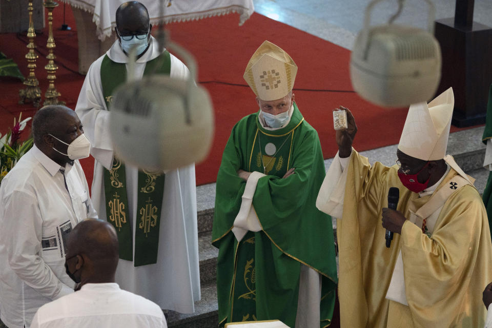 Cardinal Jean-Pierre Kutwa, right, holds up an rosary beads before giving it to the former Ivorian president Laurent Gbagbo, left, during a Mass at the Saint Paul's cathedral in Abidjan, Ivory Coast, Sunday, June 20, 2021. Gbagbo, who has returned to the country after nearly a decade, was extradited to the International Criminal Court at The Hague in 2011 and spent eight years awaiting trial on war crimes charges. A judge acquitted him in 2019, saying prosecutors had failed to prove their case. (AP Photo/Leo Correa)