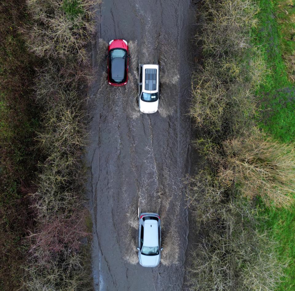 Cars travel along a flooded road after heavy rain, in Wolverhampton (REUTERS)