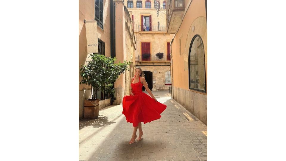 Zara McDermott smiles as she walks through street in red dress in Majorca