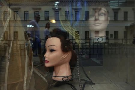 Passers-by are reflected in the window of a hair salon in Nizhny Novgorod, Russia, June 30, 2018. REUTERS/Damir Sagolj
