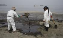 Workers, dressed in protective suits, continue to clean the oil contaminated Conchitas Beach, in Ancon, Peru, Thursday, Jan. 20, 2022. The oil spill on the Peruvian coast was caused by the waves from an eruption of an undersea volcano in the South Pacific nation of Tonga. (AP Photo/Martin Mejia)