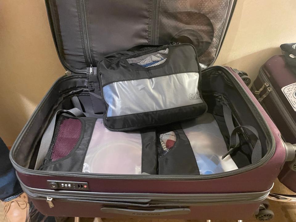 A photo of multiple packing cubes stacked in an open purple suitcase.