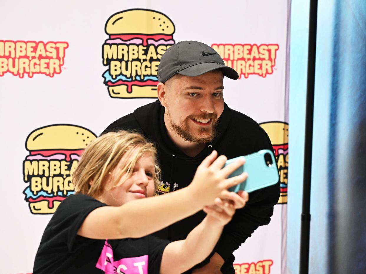 MrBeast takes a selfie with a fan at a MrBeast Burger event.