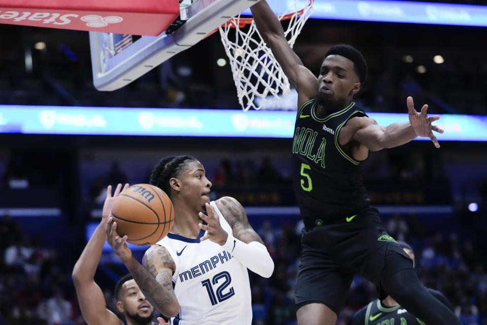 Memphis Grizzlies guard Ja Morant (12) looks to pass around New Orleans Pelicans forward Herbert Jones (5) in the first half of an NBA basketball game in New Orleans, Tuesday, Dec. 19, 2023. (AP Photo/Gerald Herbert)