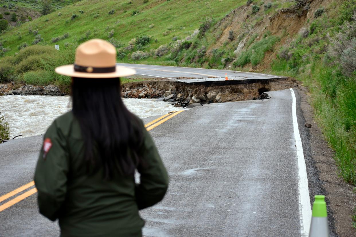 A Yellowstone National Park ranger is seen standing near a road wiped out by flooding along the Gardner River the week before, near Gardiner, Mont., on Sunday.