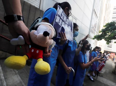 Secondary school students hold a Mickey Mouse stuffed doll with an eye patch as they form a human chain during a protest against what they say is police brutality against protesters, after clashes at Wan Chai district in Hong Kong