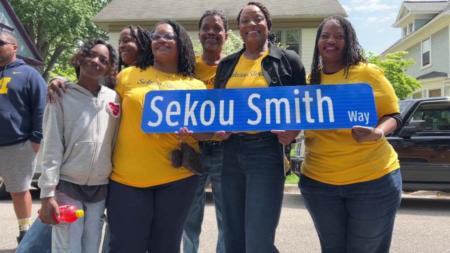 Family of Sekou Smith hold a road sign honoring him. (May 15, 2024)