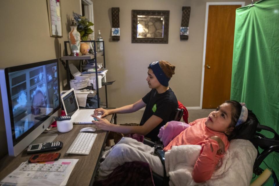 Hannah Lopez listens to a California High School teacher on her computer while her brother Lucas Lopez works next to her.