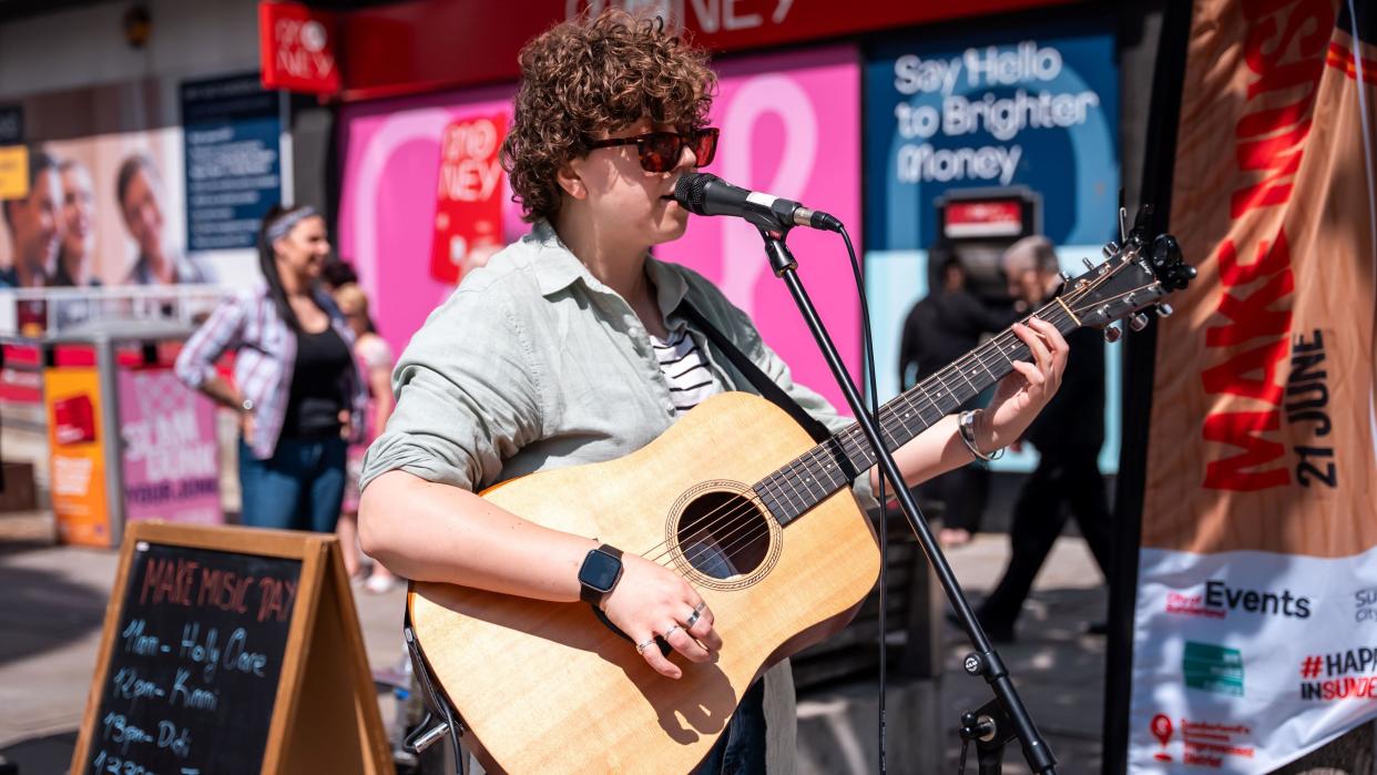 A performer playing a guitar on Make Music Day