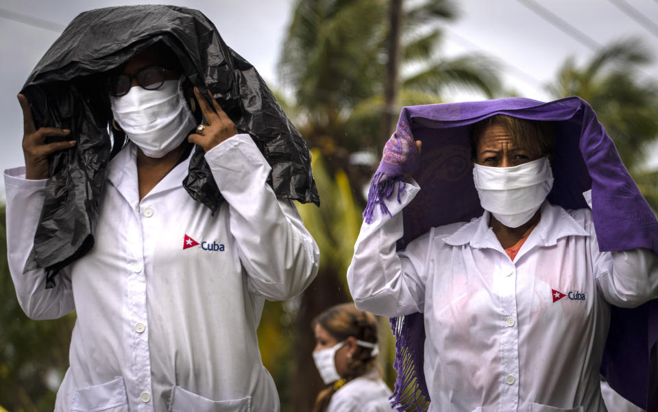 Health professionals who volunteered to travel to Kuwait to treat of coronavirus patients walk in the rain after attending their farewell ceremony in Havana, Cuba, Thursday, June 4, 2020. (AP Photo/Ramon Espinosa)