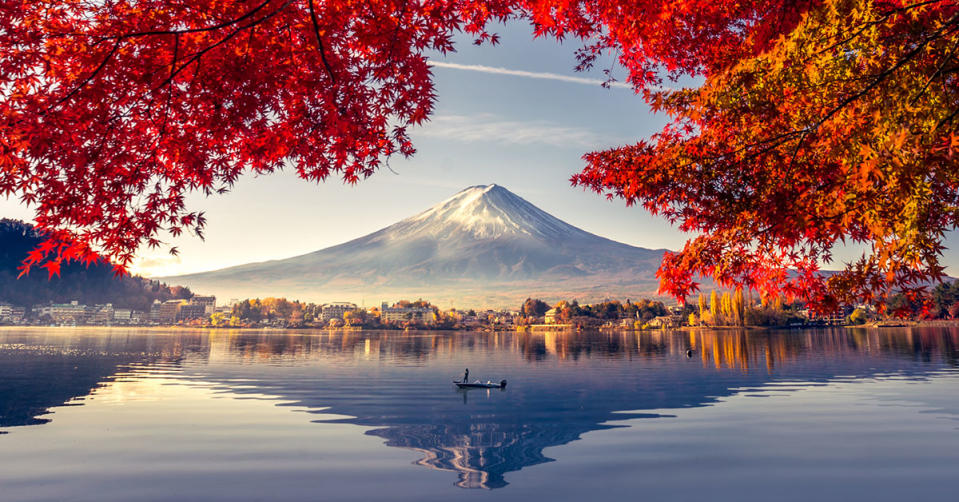 Mount Fuji by a lake in Japan surrounded by red autumn leaves