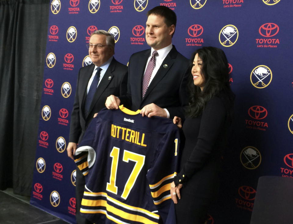 FILE - In this May 11, 2017, file photo, newly hired Buffalo Sabres' General Manager Jason Botterill, center, flanked by Terry and Kim Pegula, displays his Sabres jersey at First Niagara Center in Buffalo, N.Y. The Buffalo Sabres fired general manager Jason Botterill on Tuesday, June 16, 2020, in a dramatic change-of-course three weeks after co-owner Kim Pegula said his job was secure. In announcing the decision, the Sabres promoted senior vice president of business administration Kevyn Adams as Botterill’s successor. (AP Photo/John Wawrow, FIle)