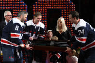 Washington Capitals center Nicklas Backstrom, third from left, is presented with golf clubs by left wing Alex Ovechkin (8) and defenseman John Carlson (74) during a ceremony to honor Backstrom for recording his 1,000th NHL point before an NHL hockey game against the New Jersey Devils, Saturday, March 26, 2022, in Washington. (AP Photo/Nick Wass)