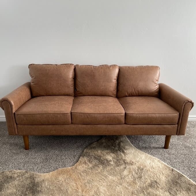 Reviewer's photo of brown pleather couch with rug.