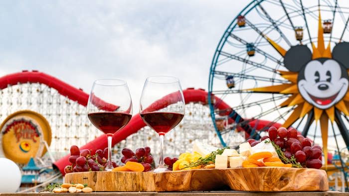 Two glasses of red wine and a cheese platter at Disneyland with Mickey's Ferris Wheel in the background