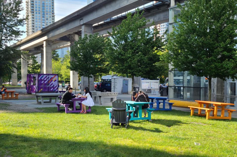 Burnaby residents enjoying the sunshine and the new picnic tables and benches near the Metrotown SkyTrain station