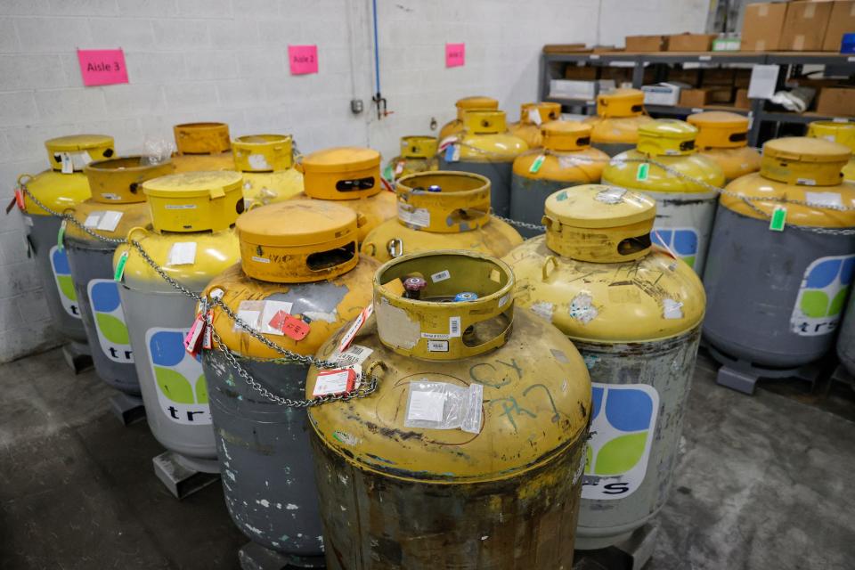 yellow and grey gas tanks lined up on a warehouse floor