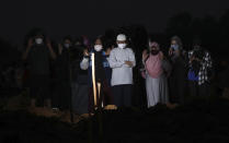 Family members pray during a burial of their relative at the special section of the Pedurenan cemetery designated to accommodate the surge in deaths during the coronavirus outbreak in Bekasi, West Java, Indonesia, Friday, July 30, 2021.(AP Photo/Achmad Ibrahim)