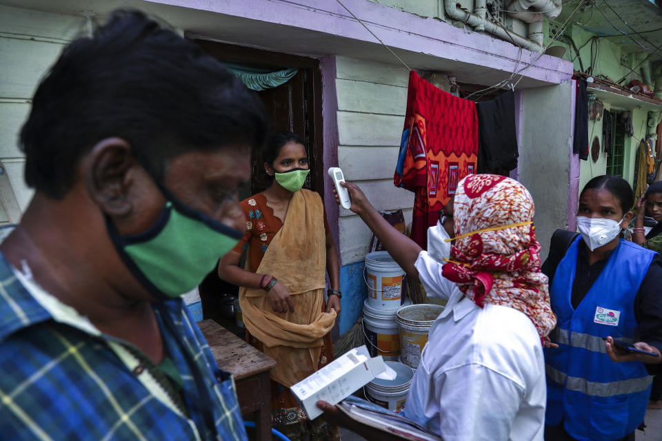 An Indian health worker checks body temperature of a woman during a door-to-door survey being conducted as a precaution against COVID-19 in Hyderabad, India, Thursday, May 6, 2021. (AP Photo/Mahesh Kumar A.)