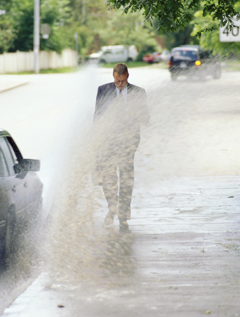 A man being splashed with mud by a passing car – an offence if you're in NSW and also splashing someone at a bus stop.