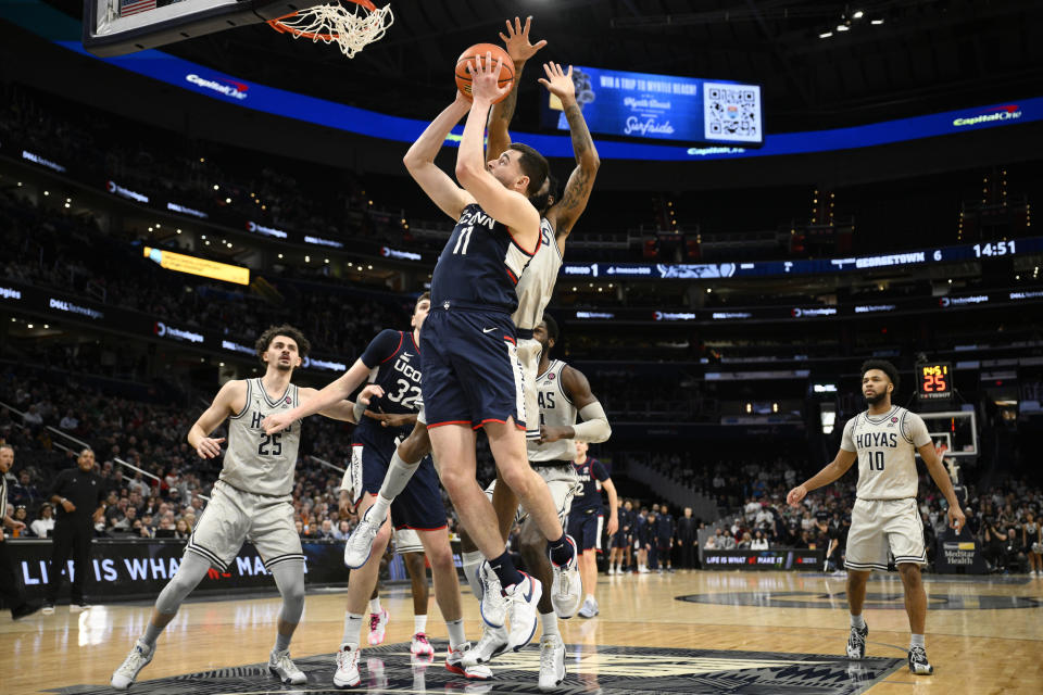 Connecticut forward Alex Karaban (11) goes to the basket against Georgetown guard Dontrez Styles, left center, forward Ismael Massoud (25) and guard Jayden Epps (10) during the first half of an NCAA college basketball game, Saturday, Feb. 10, 2024, in Washington. (AP Photo/Nick Wass)