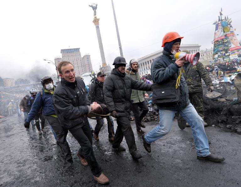 Anti-government protesters carry a fellow demonstor who was wounded during clashes with riot police in central Kiev on February 20, 2014