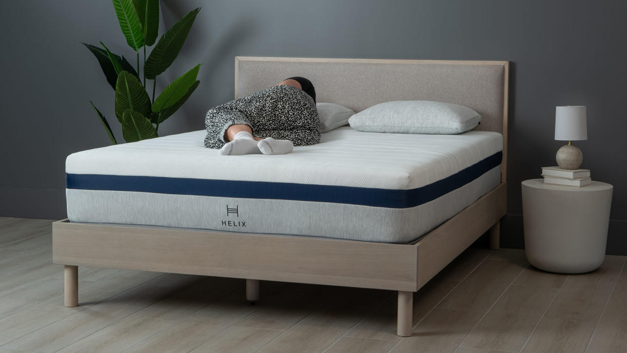  Helix Midnight mattress review: mattress on a wooden bedframe, with our reviewer asleep on her side. 