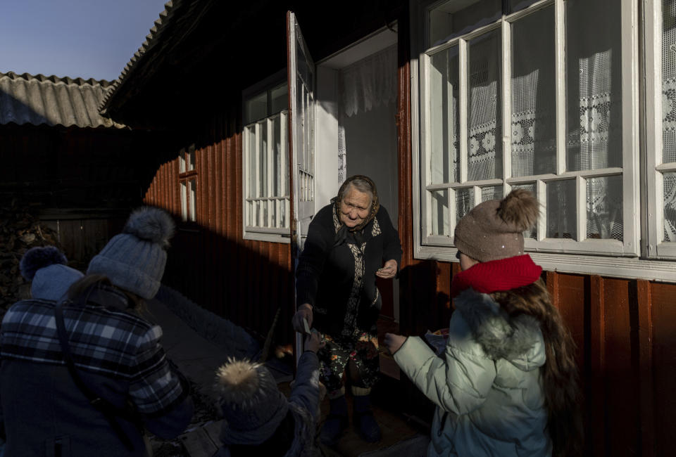 Children are handed money as a gift while celebrating the Malanka festival in the village of Krasnoilsk, Ukraine, Thursday, Jan. 13, 2022. (AP Photo/Ethan Swope)