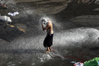 An anti-government protester takes a shower in after he asked a riot police to spray him by water cannon, where protesters have been gathering for four weeks, in front of the government palace in Beirut, Lebanon, Friday, Nov. 15, 2019. Protesters have been holding demonstrations since Oct. 17 demanding an end to widespread corruption and mismanagement by the political class that has ruled the country for three decades. (AP Photo/Bilal Hussein)