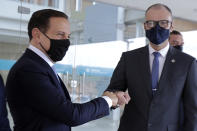 Sao Paulo Gov. Joao Doria, left, greets the Director of Brazil's National Health Surveillance Agency Antonio Barra, upon his arrival to the agency's headquarters for a meeting on the CoronaVac vaccine, in Brasilia, Brazil, Wednesday, Oct. 21, 2020. Brazil’s President Jair Bolsonaro rejected on Wednesday the announced purchase of 46 million doses of the potential vaccine being developed by a Chinese company and tested in Sao Paulo, a state governed by his political rival, prompting concern he was allowing politics to steer public health decisions. (AP Photo/Eraldo Peres)