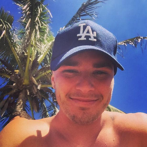 Luke Hansen smiling under a palm tree. 