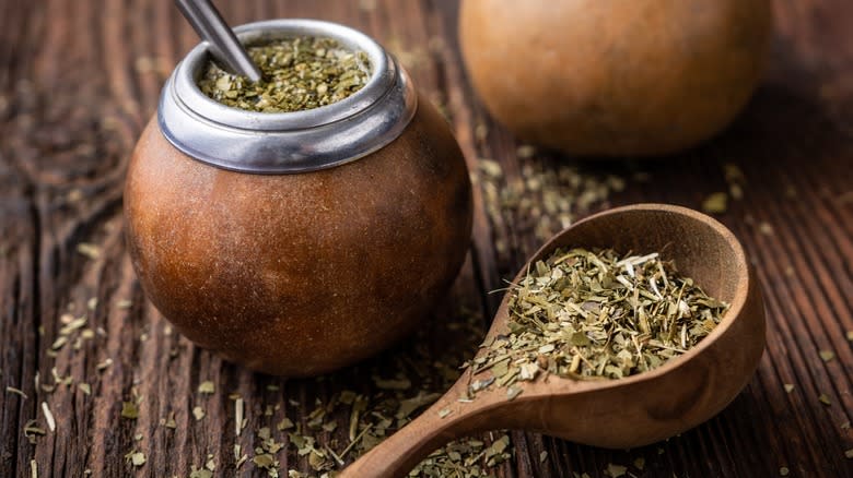 Maté in a gourd next to a spoonful of dried maté