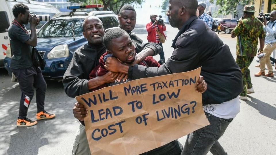 Kenyan plain clothed police officers detain an activist during a protest over tax hike plans in Nairobi on June 6, 2023.