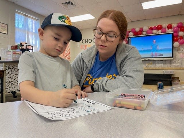 Crane Preschool Teacher Sidnie Blevins reviews a worksheet with 4-year-old Archer Chapman.