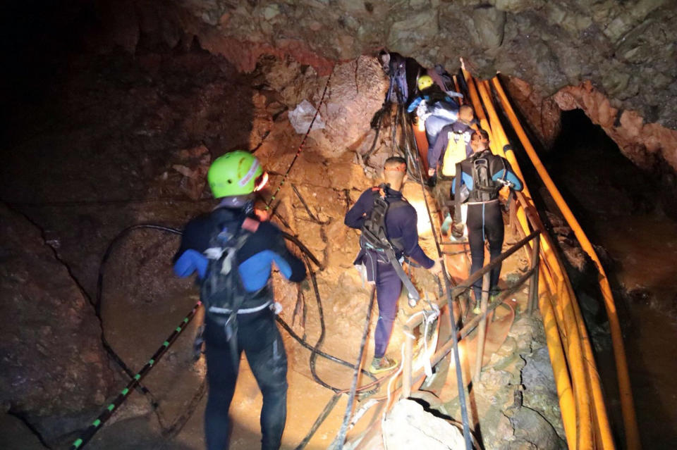 In this undated photo released by Royal Thai Navy on Saturday, July 7, 2018, Thai rescue team members walk inside the flooded cave.