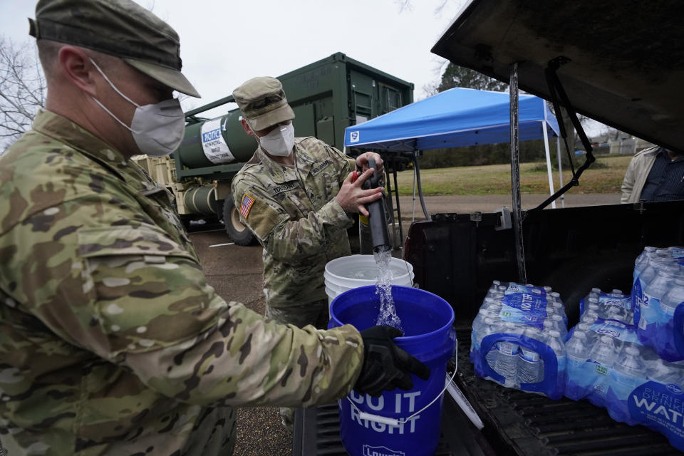 FILE - Mississippi Army National Guard Sgt. Chase Toussaint, right, and Staff Sgt. Matthew Riley, both with the Maneuver Area Training Equipment Site of Camp Shelby, fill 5-gallon water drums with non-potable water, March 1, 2021, at a Jackson, Miss., water distribution site. Up to 40,000 Army National Guard soldiers across the country - or about 13% of the force — have not yet gotten the mandated COVID-19 vaccine, and as the deadline for shots looms, at least 14,000 of them have flatly refused and could be forced out of the service. (AP Photo/Rogelio V. Solis, File)