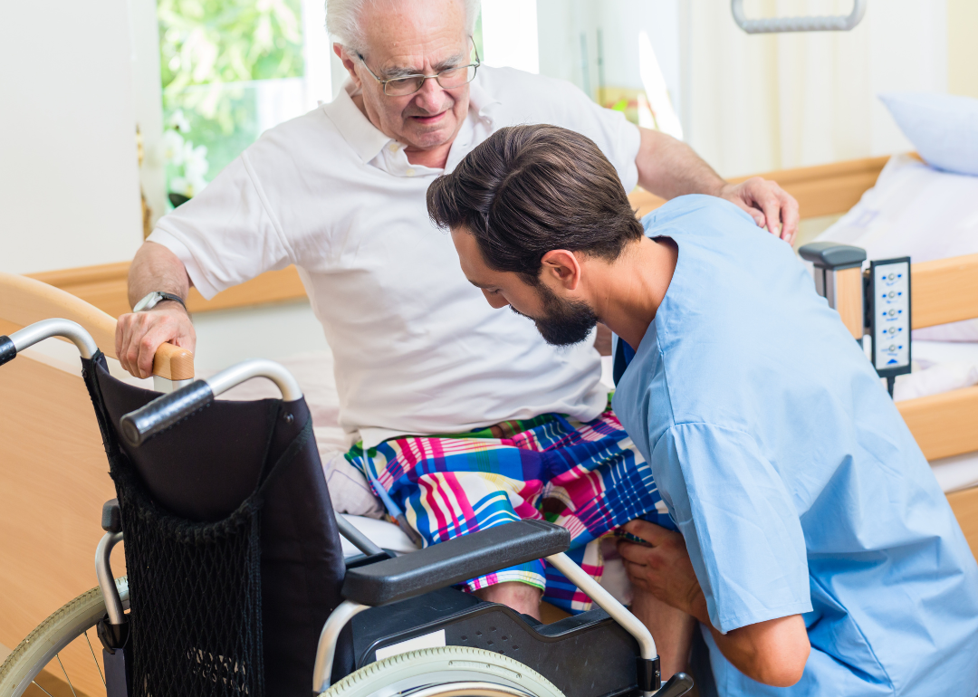 A nurse helping a patient out of a wheelchair.